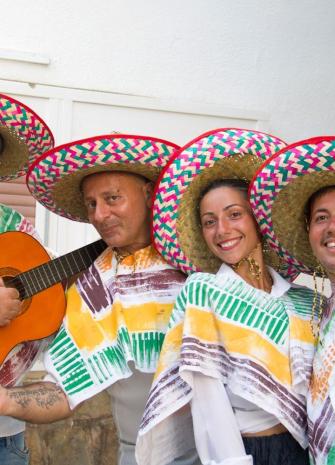 Gruppo in abiti tradizionali messicani con sombreri colorati e chitarra.