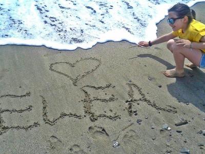 Bambina scrive 'Ewa' sulla sabbia con un cuore.