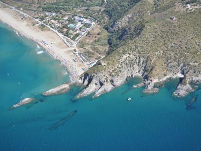 Vista aerea di una spiaggia con scogli e mare blu.