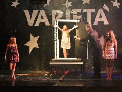 Spettacolo di magia con ragazze e illusionista sul palco.