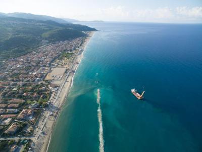 Vista aerea di una città costiera con nave in mare.