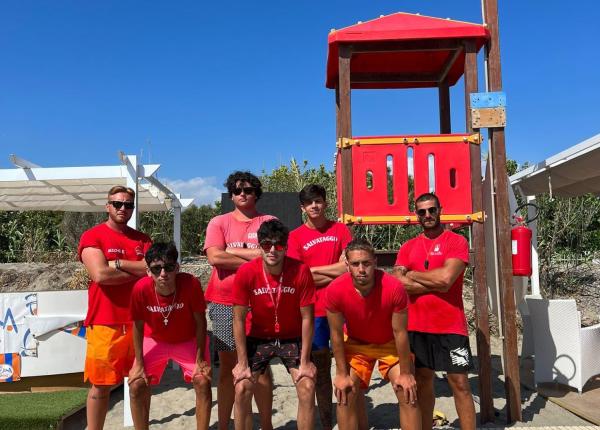 Nageurs sauveteurs posant devant une tour sur la plage.
