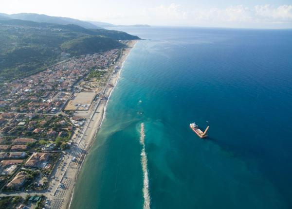 Vista aerea di una città costiera con nave in mare.