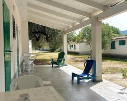 Veranda con sedie colorate, tavolo bianco e vista su giardino alberato.