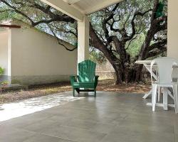 Veranda con sedia verde, albero imponente e pavimento in piastrelle grigie.