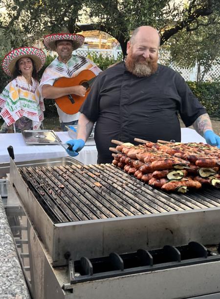 Chef sorridente griglia carne, musicisti allegri con sombrero colorati.