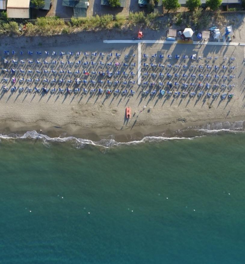 Spiaggia con ombrelloni e mare calmo, vista dall'alto.